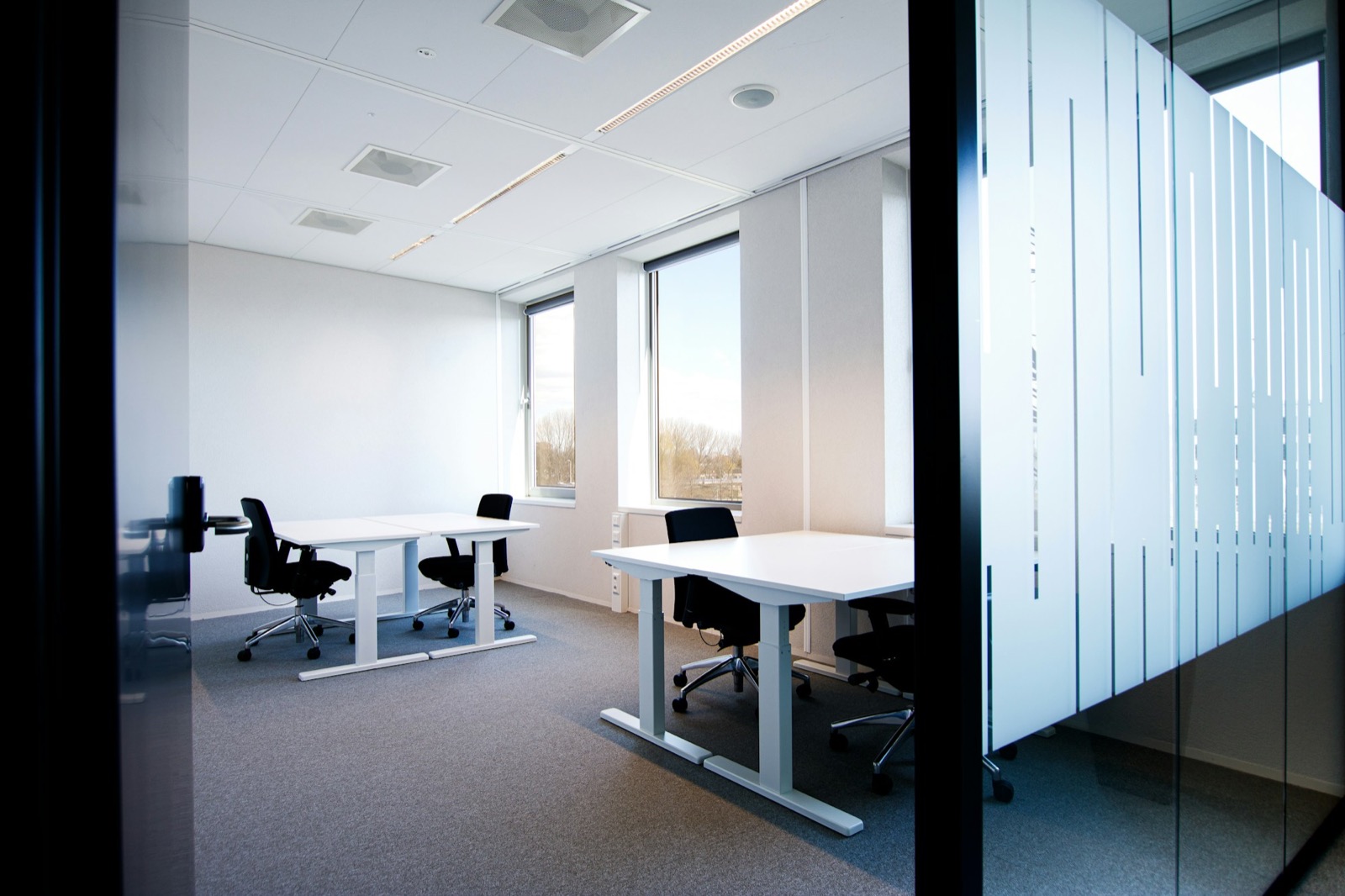 An office room with desks seen through a frosted glass partition