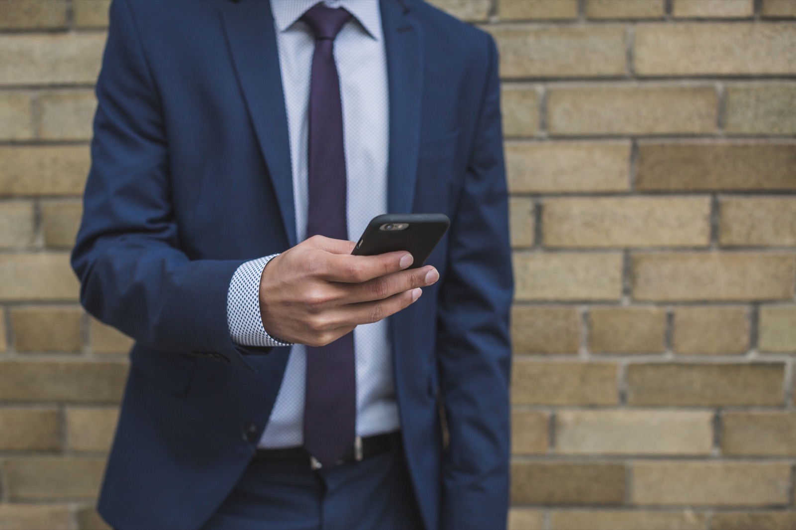 A lawyer in a suit glancing at the phone in his hand