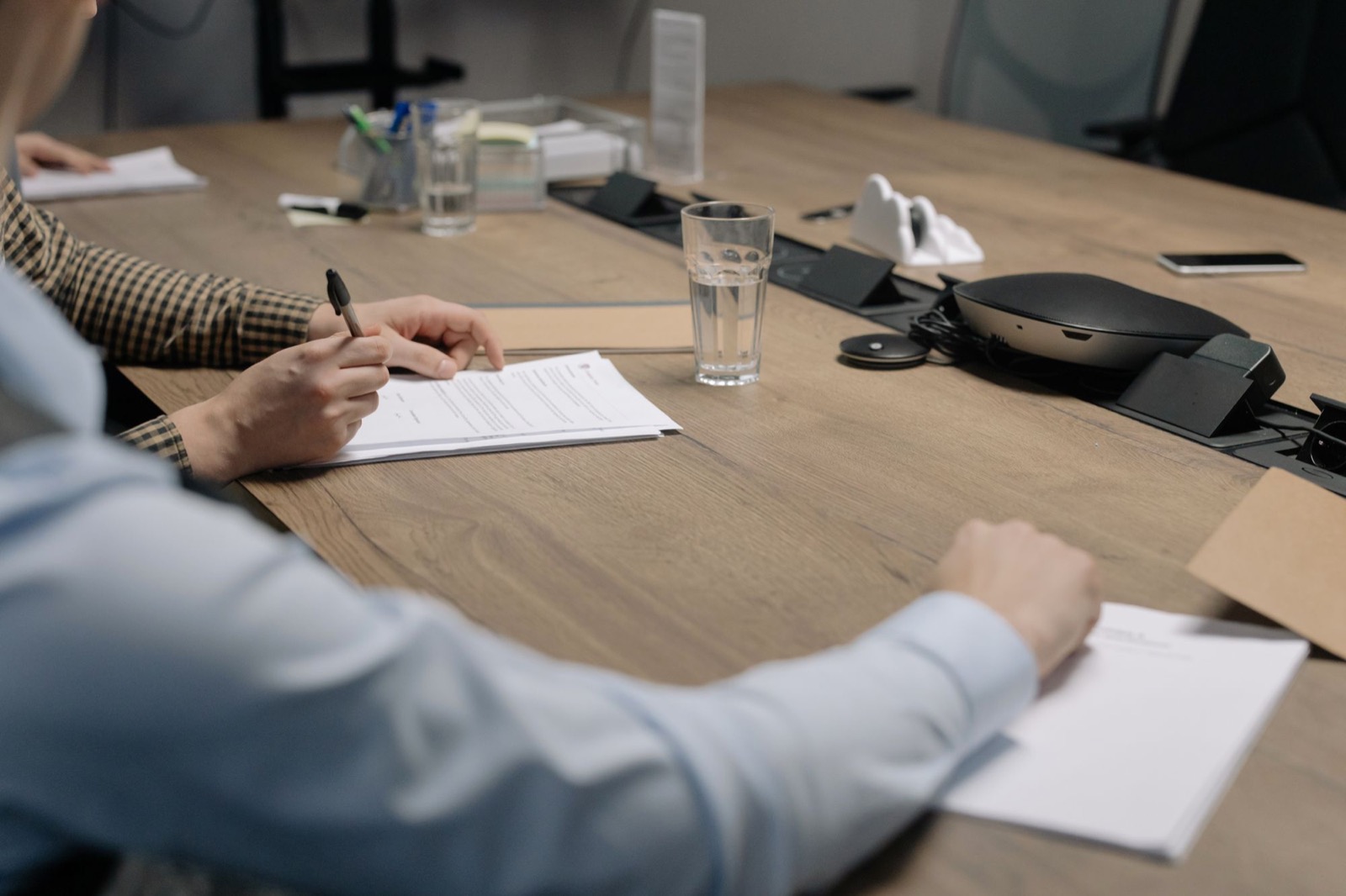 Hands signing a document at a boardroom table