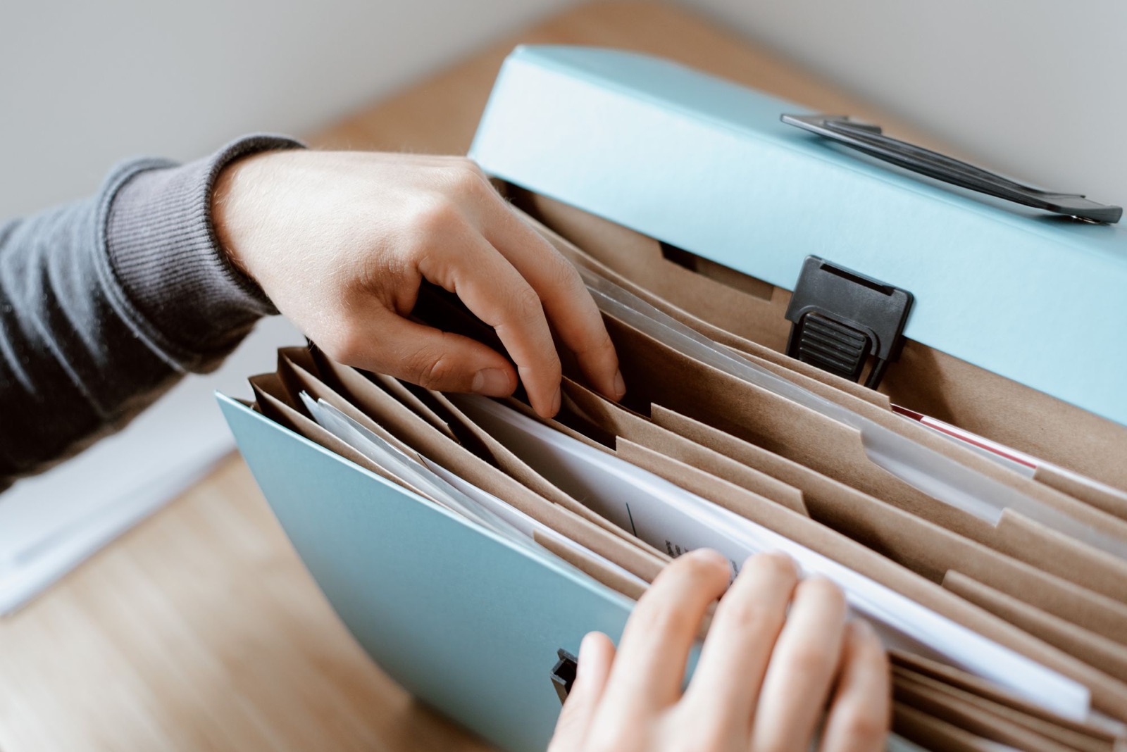 Hands picking a document out of an expanding file folder