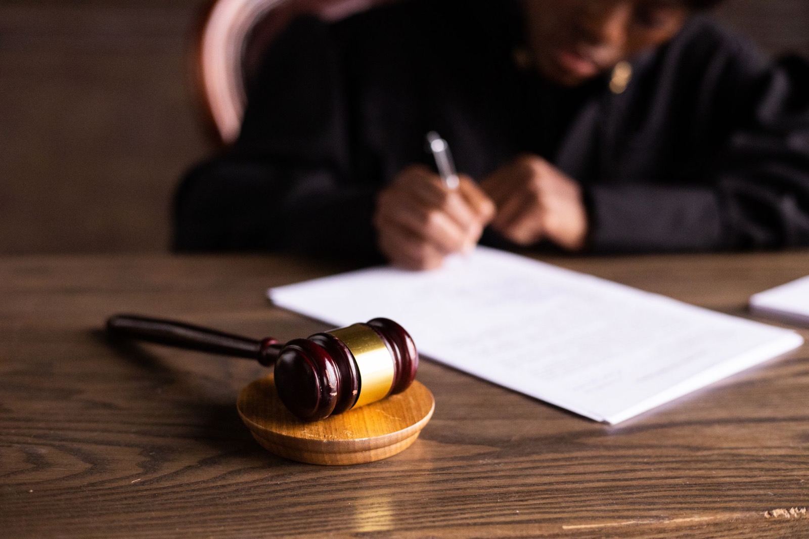 A judge signing an order, a gavel on the desk in front